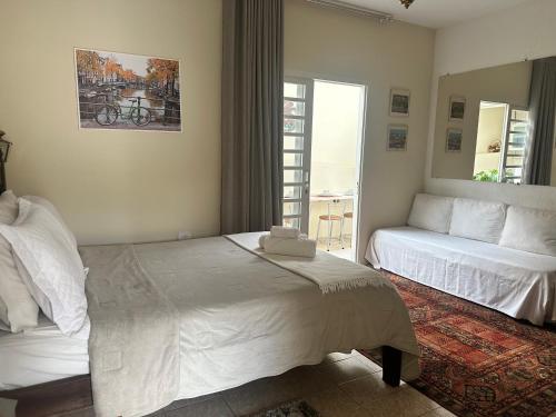 a bedroom with a white bed and a couch at Deck Hospedaria in Cunha