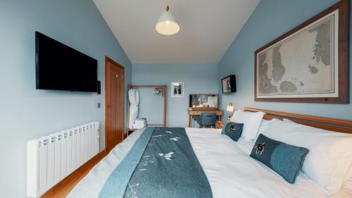 a bedroom with a large bed with a flat screen tv at Air an Oir - Skye Self Catering in Portree