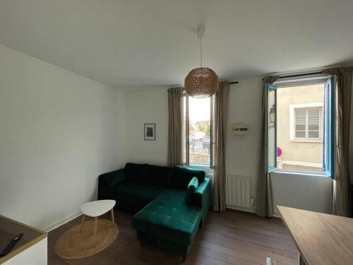 un soggiorno con divano verde e finestra di Le relais appartement aux charmes authentiques WIFI a Périgueux
