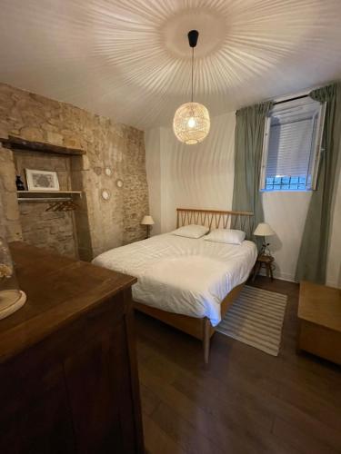 una camera con letto e lampadario a braccio di Le relais appartement aux charmes authentiques WIFI a Périgueux