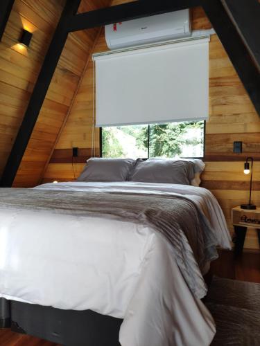 a bedroom with a white bed with a large window at Cabana Mundo Novo in Gonçalves