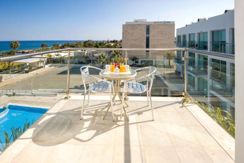 a table on a balcony with a view of the ocean at SHARON - Coralli Beachfront Apartment in Protaras