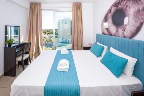 a bedroom with a blue and white bed with a desk at SHARON - Coralli Beachfront Apartment in Protaras