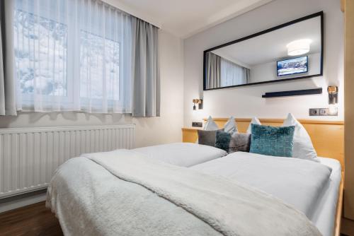 a hotel room with two beds and a mirror at Boutique Hotel ANYBODY in Saalbach Hinterglemm