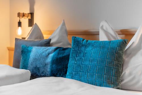 a bed with blue and white pillows on it at Boutique Hotel ANYBODY in Saalbach Hinterglemm