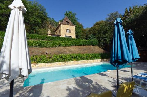 - deux parasols bleus et blancs assis à côté d'une piscine dans l'établissement Roquecombe, à La Roque-Gageac