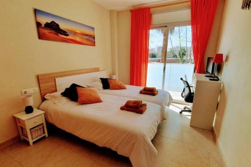 a bedroom with two beds with red curtains and a window at Eden Flat Port Aventura in Salou