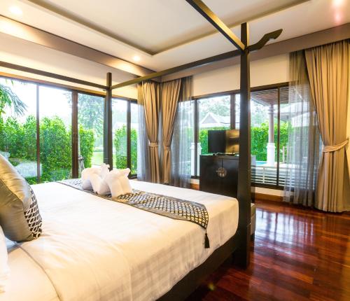 a bedroom with a large bed and a large window at Pimann Buri Pool Villas Ao Nang Krabi Sha Plus in Ao Nang Beach