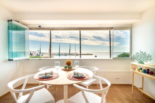 une salle à manger avec une table, des chaises et une grande fenêtre dans l'établissement MARBELLA BANUS SUITES - Marbella Beach Front Suite Apartment, à Marbella