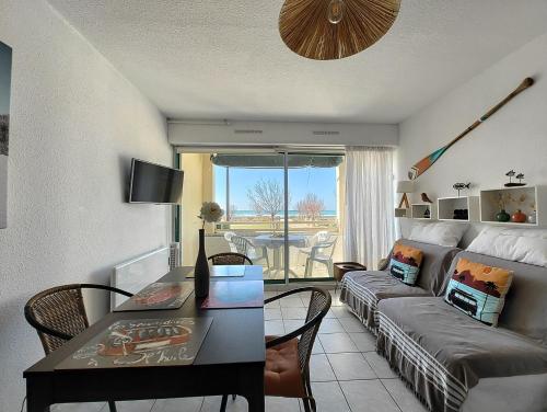 a living room with a couch and a table at Appartement La Corniche Vue océan in Mimizan-Plage