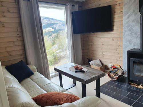 uma sala de estar com um sofá, uma mesa e uma grande janela em Molden 2-fjellutsikt og jacuzzi tilgang. em Luster