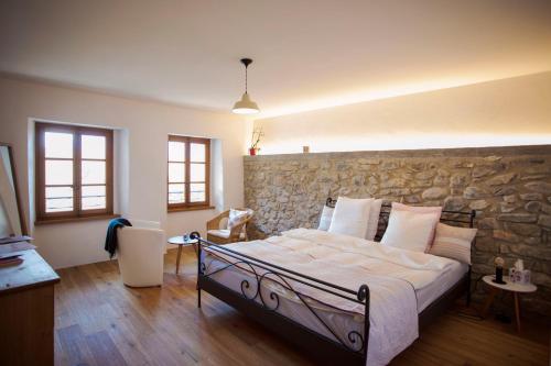 a bedroom with a bed and a stone wall at Aux Trois Soleils in Chexbres