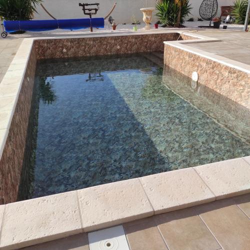 - une piscine avec un mur en pierre et une piscine dans l'établissement Studio Meublé non fumeur, à Narbonne