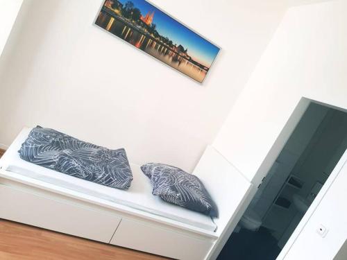 a white couch with two pillows and a picture on the wall at Helles Apartment in Neutraubling