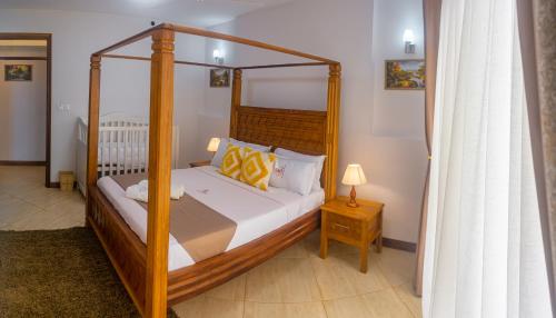 ein Schlafzimmer mit einem Himmelbett und einem Tisch mit einer Lampe in der Unterkunft The Zanakri homes Oceanfront in Mombasa