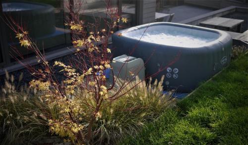 a bath tub sitting in the grass next to a plant at Rock and chill house with jacuzzi Namur Ardennes in Namur