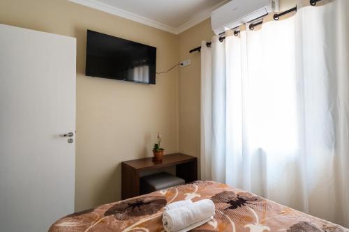 a bedroom with a bed and a television on the wall at Hostel B2B SP in Sao Paulo