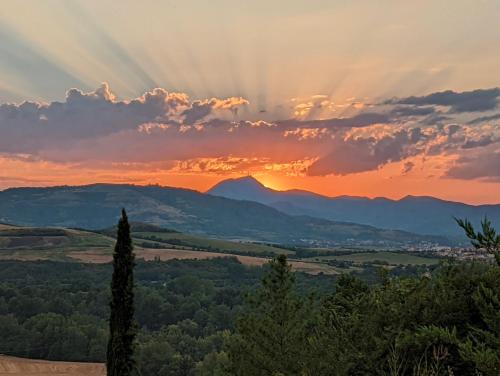a sunset in the mountains with the sun shining through the clouds at Bienvenue chez Séverine et julien Appartement 75m2 in Mirefleurs
