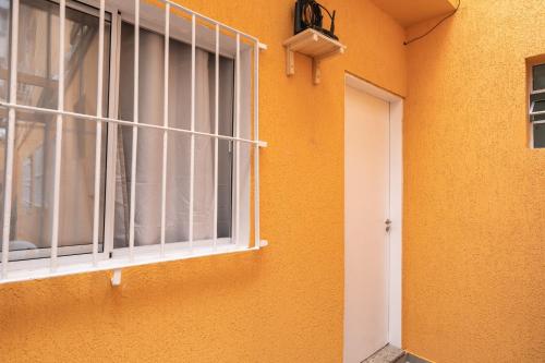 an orange wall with a window and a door at Hostel B2B SP in Sao Paulo