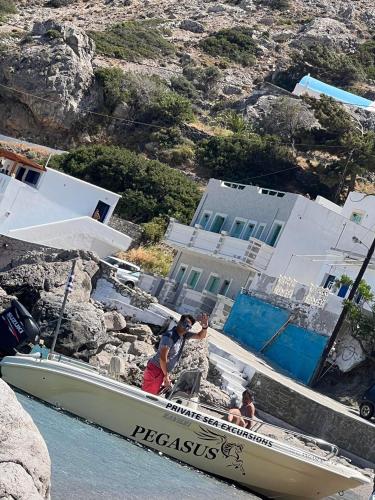 two people are standing on a boat in the water at TO VOTSALO-beach side studios & taverna in Karpathos Town