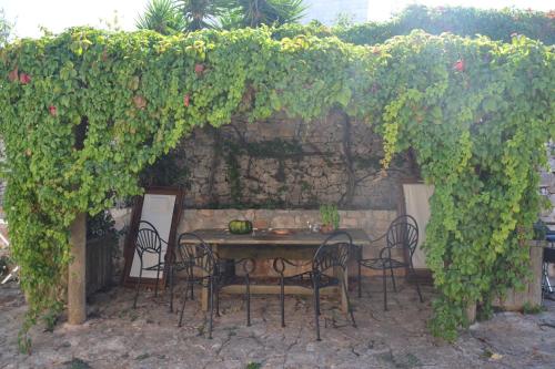 a table and chairs under an arch covered in vines at Masseria Montanaro in Cisternino