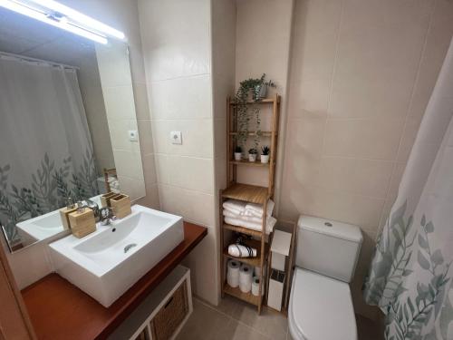 a bathroom with a sink and a toilet and a mirror at Apartamento con Piscina y Jardín Espectacular Cala Sirenas - Nuevo in Miami Platja
