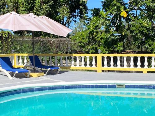 a swimming pool with two chairs and an umbrella at Yancey Largo Villa with Private Pool in Montego Bay