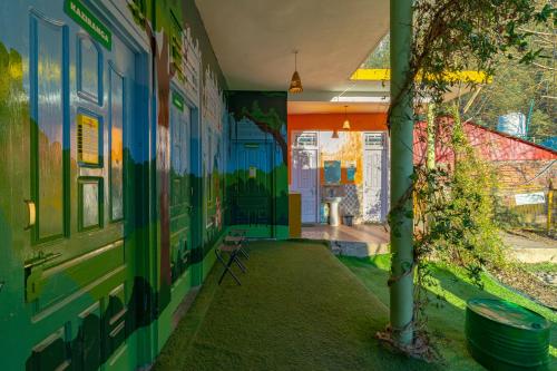a hallway with painted walls and a tree in a house at Jungle Hostel by Whoopers in Kasol