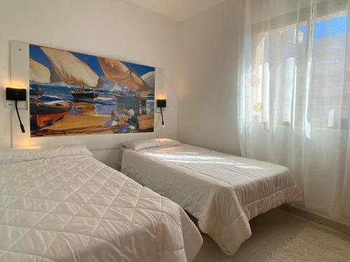 a bedroom with two beds and a painting on the wall at Sunrise Studio Sorolla, 150 m de la playa in Miami Platja