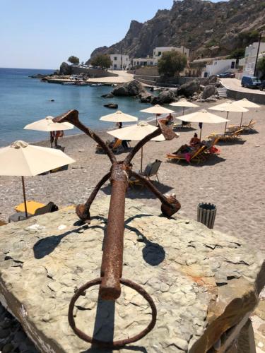 a metal object on a beach with umbrellas at TO VOTSALO-beach side studios & taverna in Karpathos Town