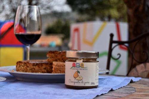 a jar of jam next to a plate of bread and a glass of wine at Cascina Tre Botti in Agliano Terme