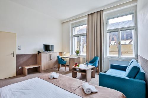 a hotel room with a bed and a blue chair at Apartments Embassy by LH in Prague