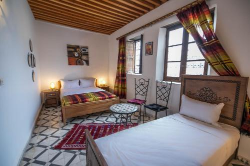 um quarto com 2 camas, uma mesa e janelas em Dar Fez Unique em Fez