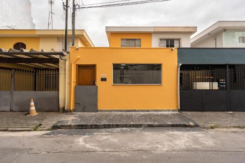 a yellow house on a street with a gate at Hostel B2B SP in Sao Paulo