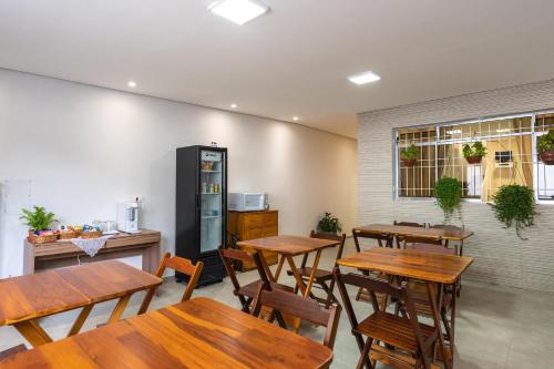 a restaurant with wooden tables and chairs and a refrigerator at Hostel B2B SP in Sao Paulo