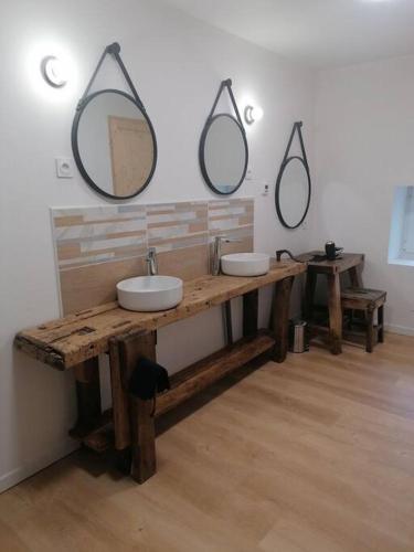 La salle de bains est pourvue de 2 lavabos et de 2 miroirs sur le mur. dans l'établissement Gîte 1921, à Vendeuvre