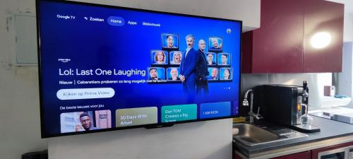a large television screen on a wall in a kitchen at Logeerkamer XXL 25 m2 in Zemst
