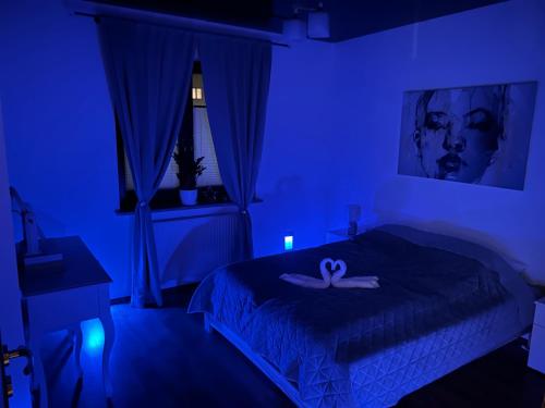 Una habitación azul con una cama con una cinta. en Apartamenty Modrzewiowa, en Suwałki