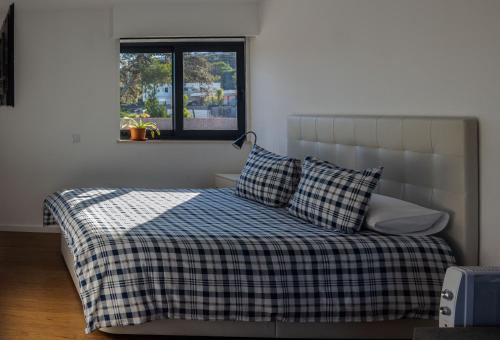 a bed with a checkered blanket and a window at Cork House in Vila Praia de Âncora