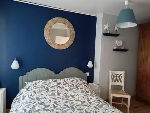 Dormitorio azul con cama y espejo en Le macareux, maison de pêcheur., en Saint-Valery-sur-Somme
