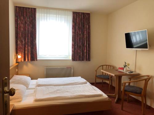 ein Hotelzimmer mit einem Bett, einem Schreibtisch und einem TV in der Unterkunft Gästehaus Kaiserkrone in Schöna