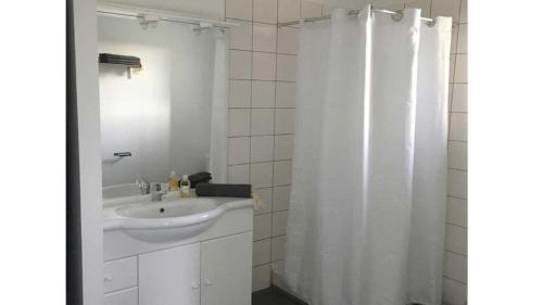 La salle de bains est pourvue d'un lavabo et d'un rideau de douche blanc. dans l'établissement Villa spacieuse avec terrasse et vue Mont Ventoux, à Entrechaux