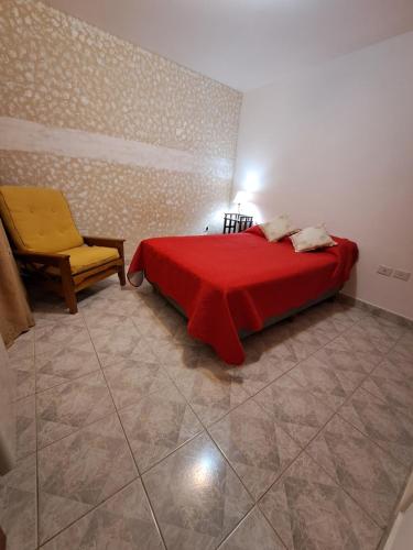 1 dormitorio con cama roja y silla amarilla en Vientos Del Sur en Río Gallegos