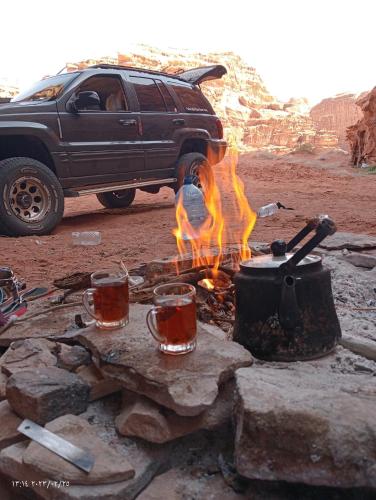 a campfire with cups of tea and a truck at golden day in Wadi Rum