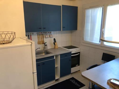 - une cuisine avec des placards bleus et un évier dans l'établissement Superbe appartement 2 chambres, à Évry-les-Châteaux