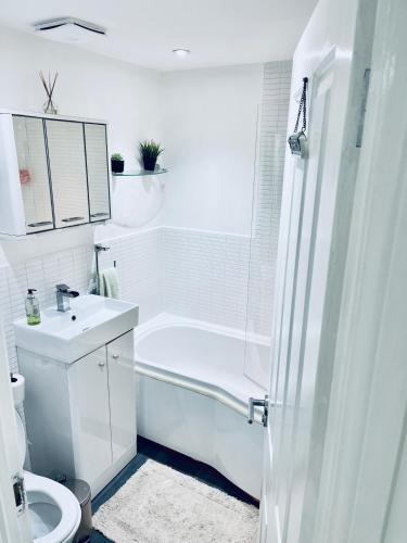 Baño blanco con bañera y lavamanos en Private room in BS14, en Bristol