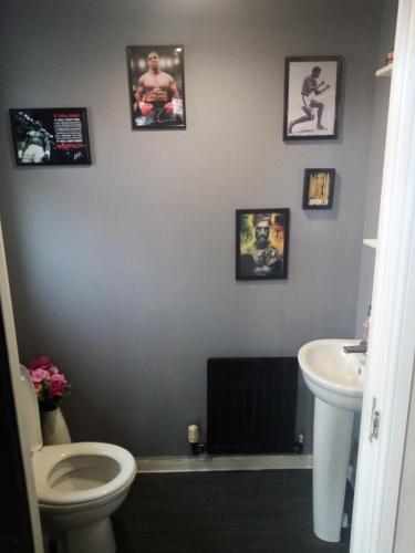a bathroom with a toilet and a sink and pictures on the wall at Private room in BS14 in Bristol