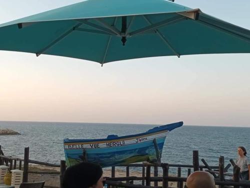 a blue umbrella and a boat on the beach at Residence les Jasmins in Sousse