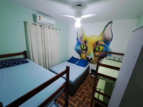 ein Zimmer mit zwei Betten und einer Katze an der Wand in der Unterkunft Recanto dos Amigos in Praia Grande