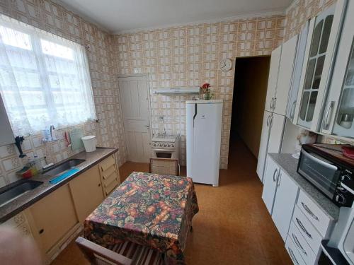 eine kleine Küche mit Tisch und Kühlschrank in der Unterkunft Recanto dos Amigos in Praia Grande